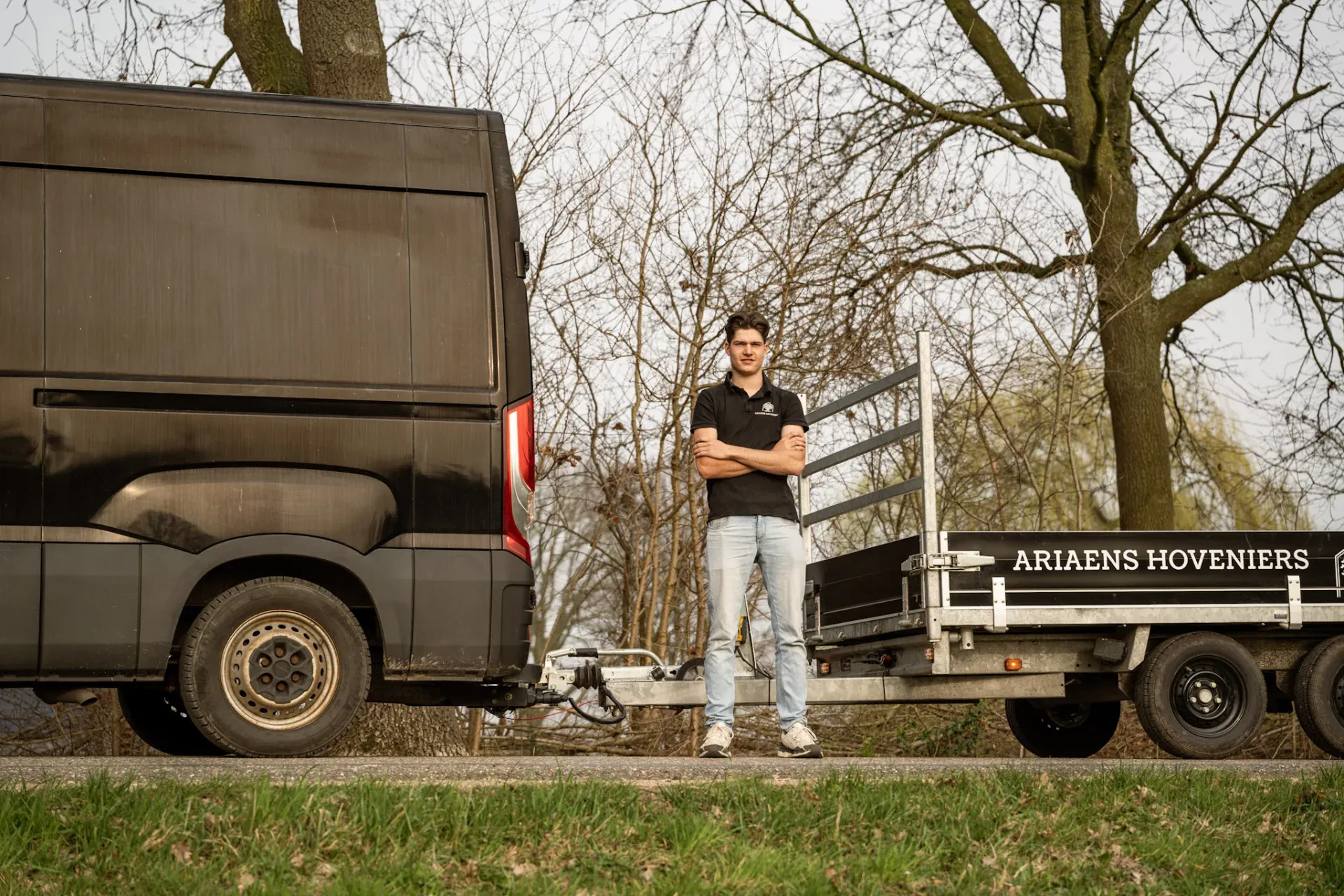 Jaap tussen de bedrijfswagen en aanhanger van Ariaens Hoveniers