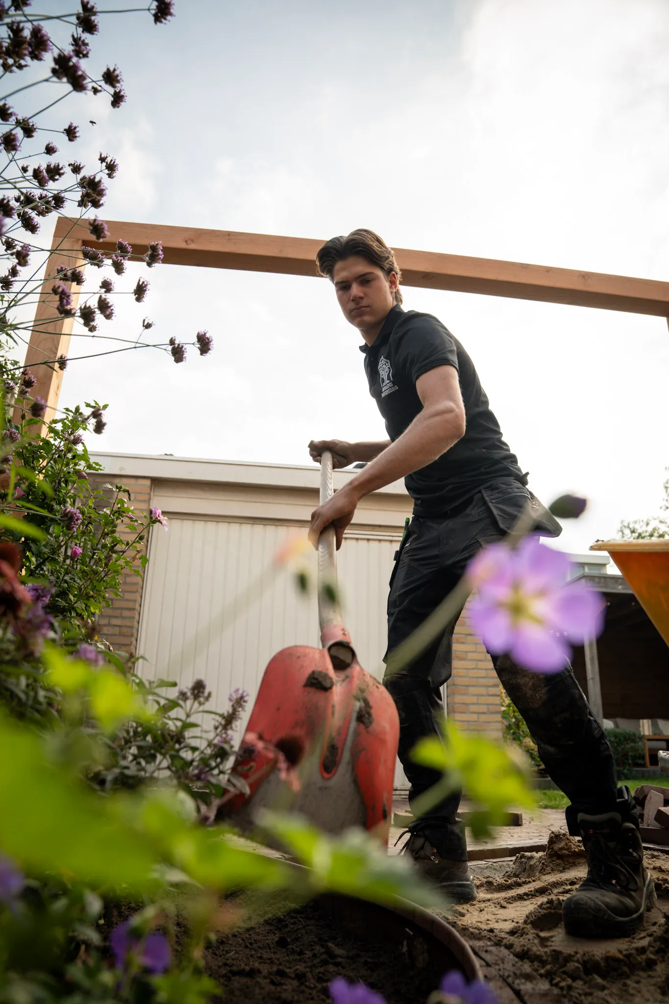 Jaap werkt met een spade tussen de planten in de tuin